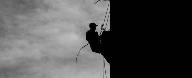 a silhouette of a man climbing a building