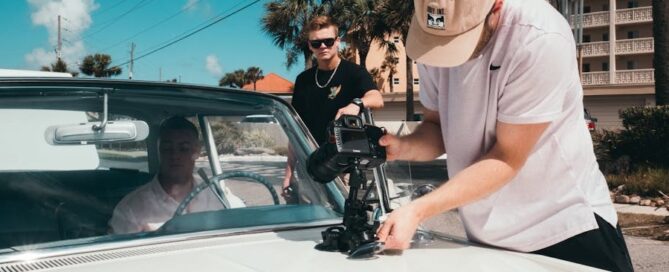 a man holding a camera to a car