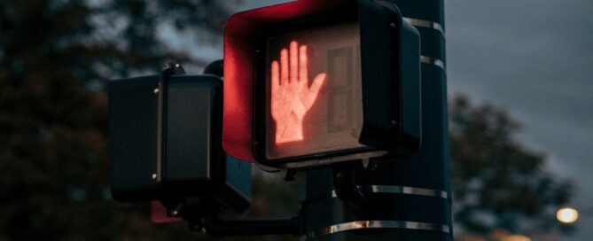 a crosswalk sign with a hand symbol