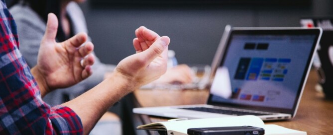 a man clapping hands in front of a laptop