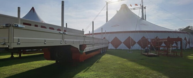 a white tent with a trailer parked on grass